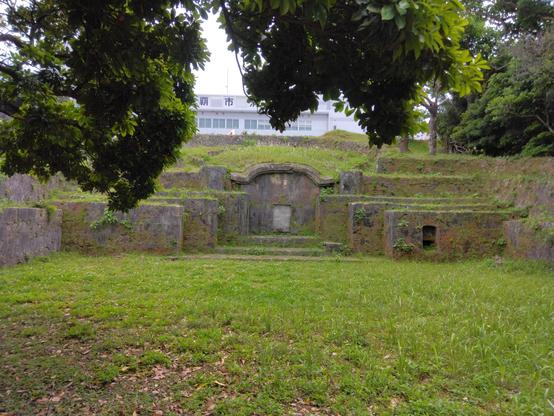 photograph of a large, huge, gigantic ryukyuan tomb, with cyclopean walls and gently covered in grass.