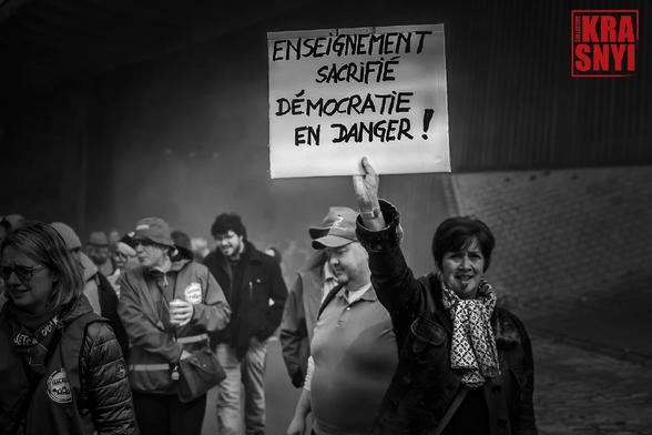 Une manifestante tient une pancarte: "ENSEIGNEMENT SACRIFIÉ, DÉMOCRATIE EN DANGER"