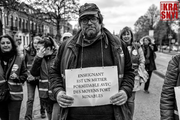 Un manifestant avec une pancarte "ENSEIGNANT EST UN MÉTIER FORMIDABLE AVEC DES MOYENS FORT MINABLES"