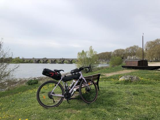 Photo. Mon vélo adossé à un banc, et en arrière plan un bout du pont de Beaugency.
