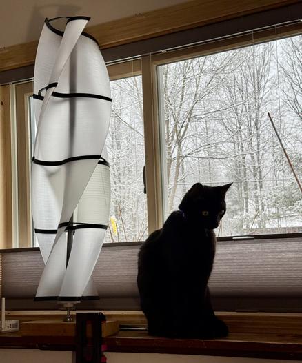 black cat for scale next to a wind spinner that is loosely mounted to a 2x4 at base as an example.