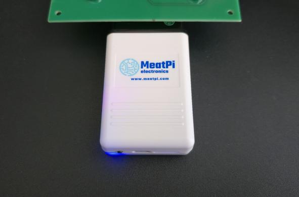 MeatPi Electronics auto diagnostic tool WiCAN PRO running plugged into OBD-2 simulator, with blue light on left bottom corner shining
