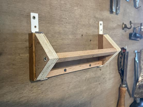 Weird structure made of various wood leftover that hangs on a vertical tool workbench