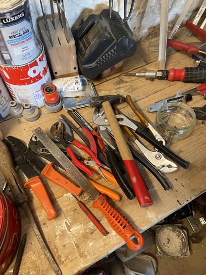 A messy workbench with all possible kinds of  pliers