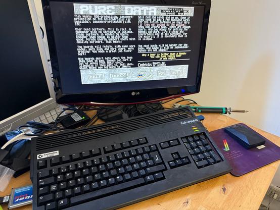 Amiga 1200 in custom black, connected via HDMI to LGMonitor. Displaying pure data #2 disk mag, bust reports section