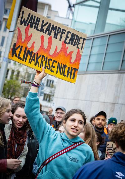 Eine weibliche Person hält in einer Menge das Schild Wahlkampf endet Klimakrise nicht hoch
