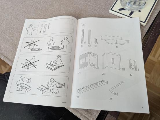 Ikea assembly instructions, opened on the first page of instructions, on a coffee table