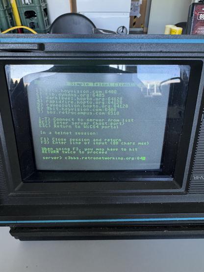 An old computer terminal displaying a green text interface. The screen shows various BBS (Bulletin Board System) connection options, including server addresses and port numbers. Instructions for connecting and navigating the session are visible, along with a prompt for user input at
