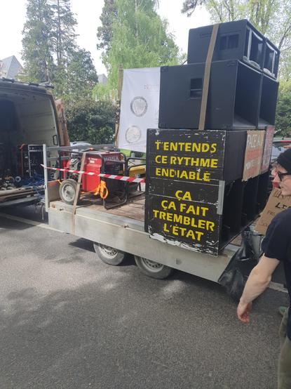 une pancarte accrochée sur des caissons de basse où il est écrit "T'entends ce rythme endiablé
ça fait tremblé l'état"