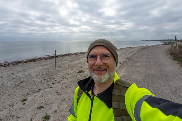 Wide angle view of a cloudy sky, DJ4RAM in front, the dune beach (baltic sea) in background and the Falshöft lighthouse on the upper right side (very far away)