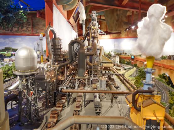 A photo of a steelworks fron the side of a model railway. Multiple railway wagons for steel can be seen.