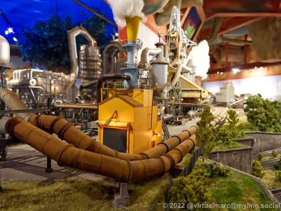 A photo of a steelworks in a model railway with rusty big pipes.