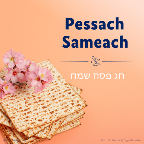 Grußkarte zu Pessach mit der Aufschrift "Pessach Sameach" in blauer Schrift und 'חג פסח שמח' (hebräisch für "Frohes Pessachfest") auf orangefarbenem Hintergrund. Links im Bild liegen mehrere Matzen (ungesäuertes Brot), darauf ein Zweig mit rosa Kirschblüten.