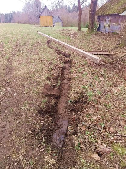 A long trace of exposed earth and knocked aside sod. In the distance, a curled up length of conveyor belt is visible, stuck under a massive concrete beam.