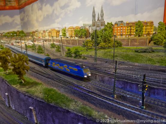 A photo of a model railway with a passenger train coming by.