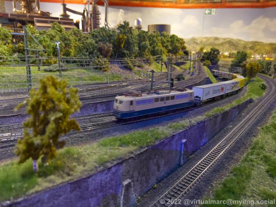 A photo of a model railway with a fright train coming by.