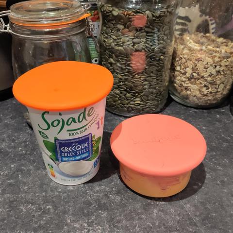 A tub of yoghurt and a tub of hummus with reusable silicone lids on. These ones come from a company called Moopops (we're in the UK)