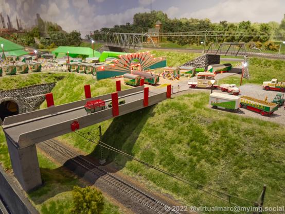 A photo of a model railway with a circus on it. Multiple wagons and en entry to the circus area.