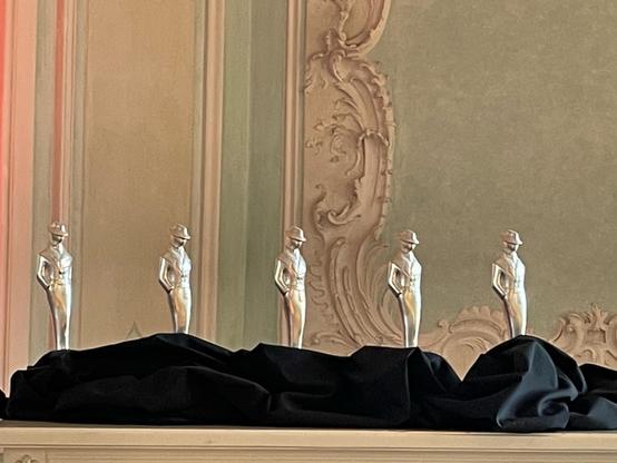 Foto der silbernen Glauser-Statuetten vor der Stuck-Wand des Mozart-Saals