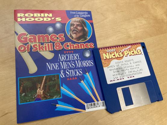 A copy of Crazy Nick's Software Picks: Robin Hood's Games of Skill & Chance. It shows a screenshot of an archery game on the cover. A 3.5-inch diskette with the same label sits beside it.