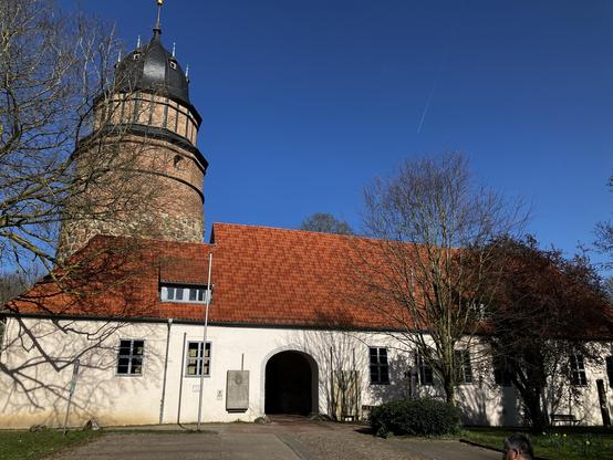 Die Burg von Diepholz mit einem mächtigen Turm. Die Wände sind weiß und das Dach mit roten Ziegeln gedeckt