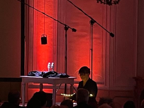 Foto von Constanze, die bei der Bühne vor den zwei verbliebenen Glauser-Statuetten aus dem Gewinnertext liest