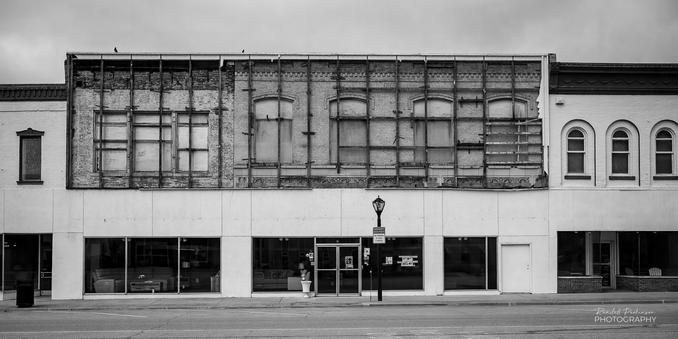 The original upper portions of two old business district buildings still have a wooden framework that used to support panels completely covering the upper portion of the building.