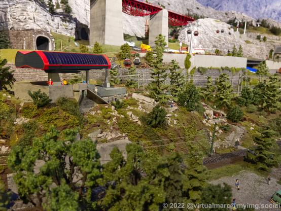 A photo of a model railway with a cablecar going up a mountain.