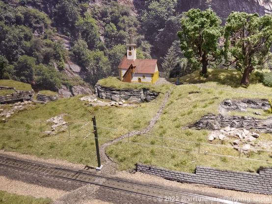 A photo of a church in the middle of the countryside in the middle of nowhere on a model railway.