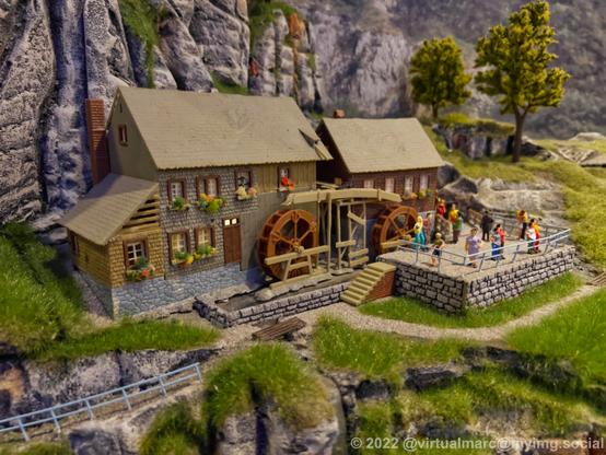 A photo of a water mill in a model railway at a mountain in the nature.