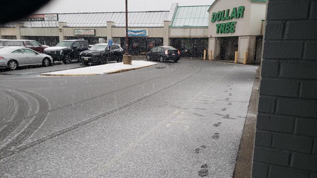 A strip mall with a snowy parking lot.