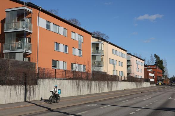 A photo of a road, apartment buildings and a cyclist on a sunny spring evening.