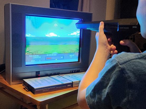 Kid playing Sega Master System light phaser games with the gun mere centimetres from the screen.