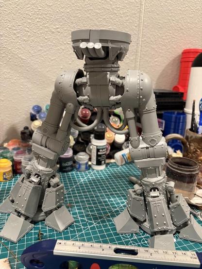 The Reaver Titan is standing up on a green cutting mat. The upper pelvis is now affixed to the lower pelvis. A level is in front of the Titan, which mostly worked out.