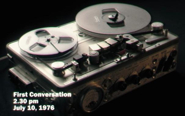 A screen capture from a fictional television documentary featured in the movie "Late Night with the Devil" (2023).

It shows an open-reel tape recorder (aka reel-to-reel) with a tape loaded on it.  The scene this is taken from shows the playback of the tape.  The tape unspools from the left-hand supply reel counter-clockwise normally, but the takeup reel on the right-hand side turns clockwise, with the tape passing to the left of the center axis of the reel.

I'm not aware of any decks that actually work this way.  There are other oddities too, like no tension arm on the supply side, an apparent tension arm on the takeup side but which is not actually in the tape path, and various other weirdnesses.