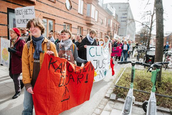 Protesters walking with banners on the sidewalk.