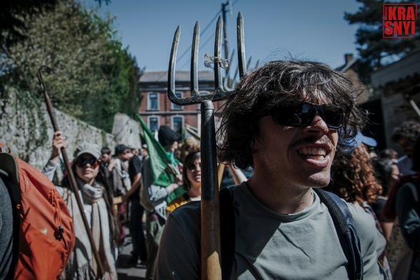 Une foule de manifestants, à l'avant plan l'un d'eux tient une fourche.