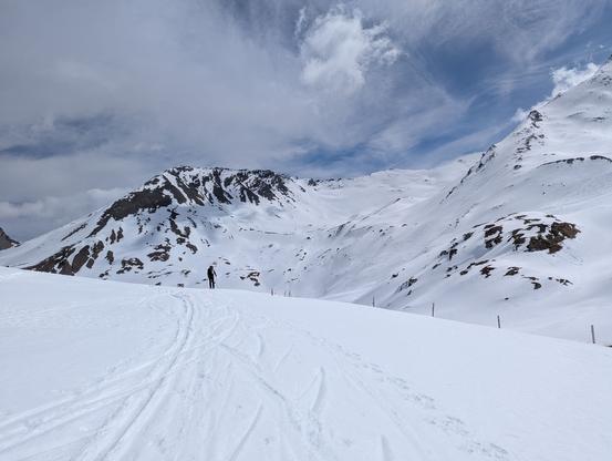 Skier on rather flat terrain with upper part of the valley behind.