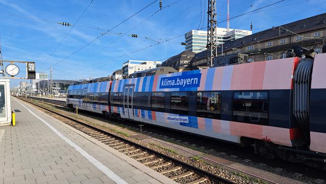 Bild zeigt einen Zug mit aufgedruckten Warmingstripes in München.