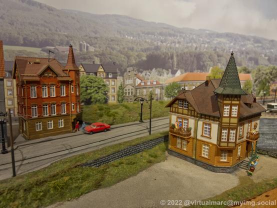 A photo of a model railway with a street and old houses around.