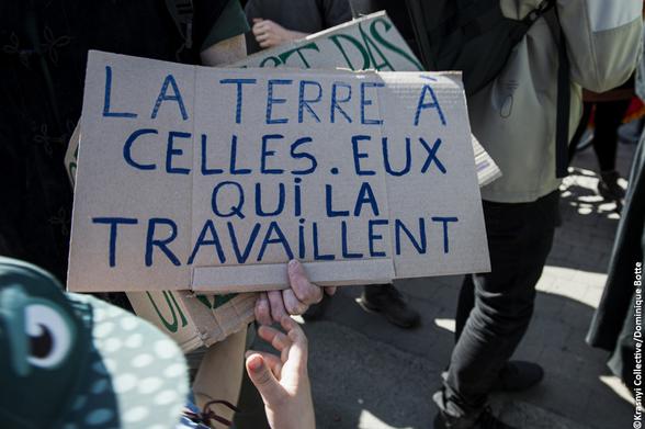 Une pancarte : "LA TERRE À CELLES.EUX QUI LA TRAVAILLENT"