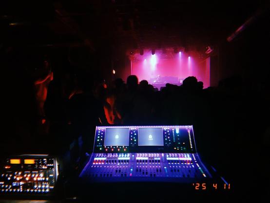 A mixing desk in front of a club's stage in blue and purple colours.