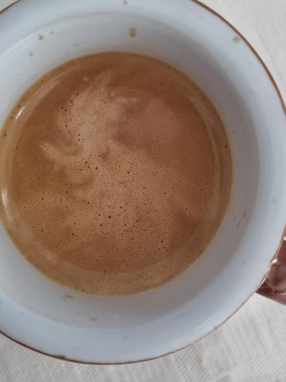 Sulla superficie del caffè, la lieve schiuma sembra disegnare una maschera, un volto di profilo, con un lungo naso, bocca aperta ed occhi, ed una cresta in testa