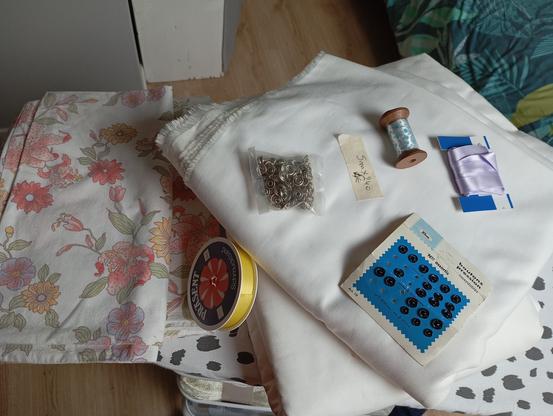 Loot de la braderie Emmaüs 
- 1 housse de couette fleurie (ton rouge et orange) vintage
- 2 coupons de tissus blanc sur lesquels sont posés
- plusieurs rubans (un bleu, un mauve et un jaune) 
- deux lots de pression à poser et à coudre
