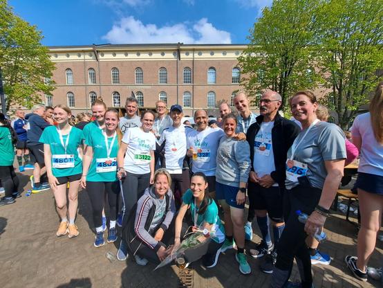 Group foto of runners (staff and students) from Saxion University of Applied Science. All completed the 5 or 10 k in Deventer at the IJsselloop. They smile, are happy, it's beautiful sunny weather.