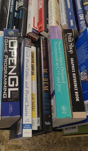 Three rows of secondhand books lined up on a table with their spines visible. "The Modem World" is visible in the first row.