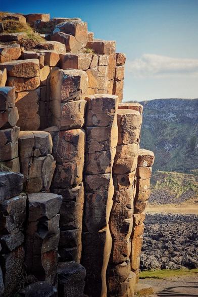A close-up shot shows the unique hexagonal basalt columns of the Giant's Causeway lit up in the bright sunshine.