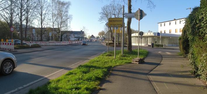 Auf einem viel zu schmalen Radweg steht hinter einem Knick ein provisorisches Verkehrszeichen mit dem Rücken zur Fahrtrichtung. Eine Absicherung des Hindernis besteht nicht.