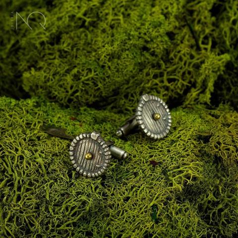 un fondo de liquen verde con un par de gemelos tallados que simulan una redonda puerta hobbit