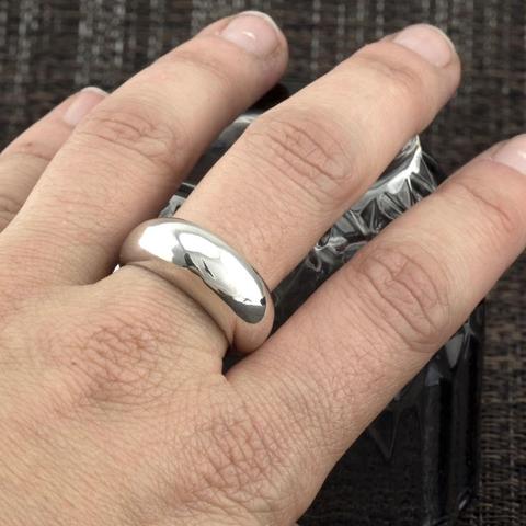 primer plano de unos dedos con un anillo de plata pulida tipo bombe